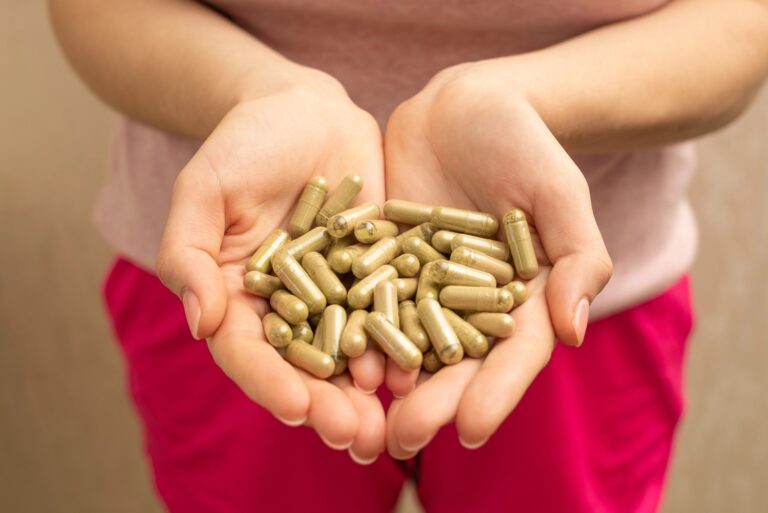 Hand holding vibrant kratom capsules, showcased at a Glass Pipes Tulsa shop.