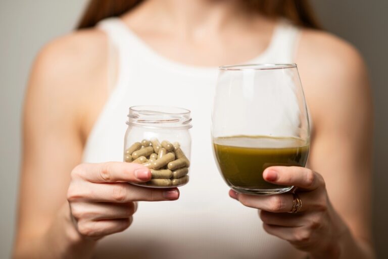 Person holding kratom capsules and a green juice glass, showcasing products at a Tulsa kratom retail store.
