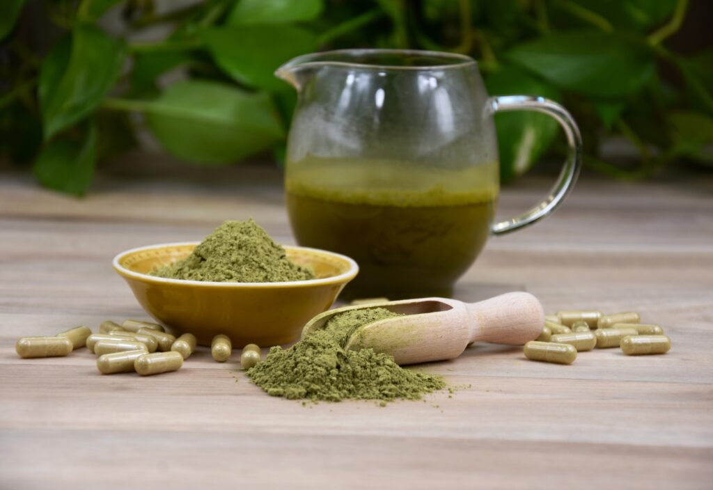Kratom powder in a bowl with capsules and juice pitcher, available at a Tulsa kratom shop.