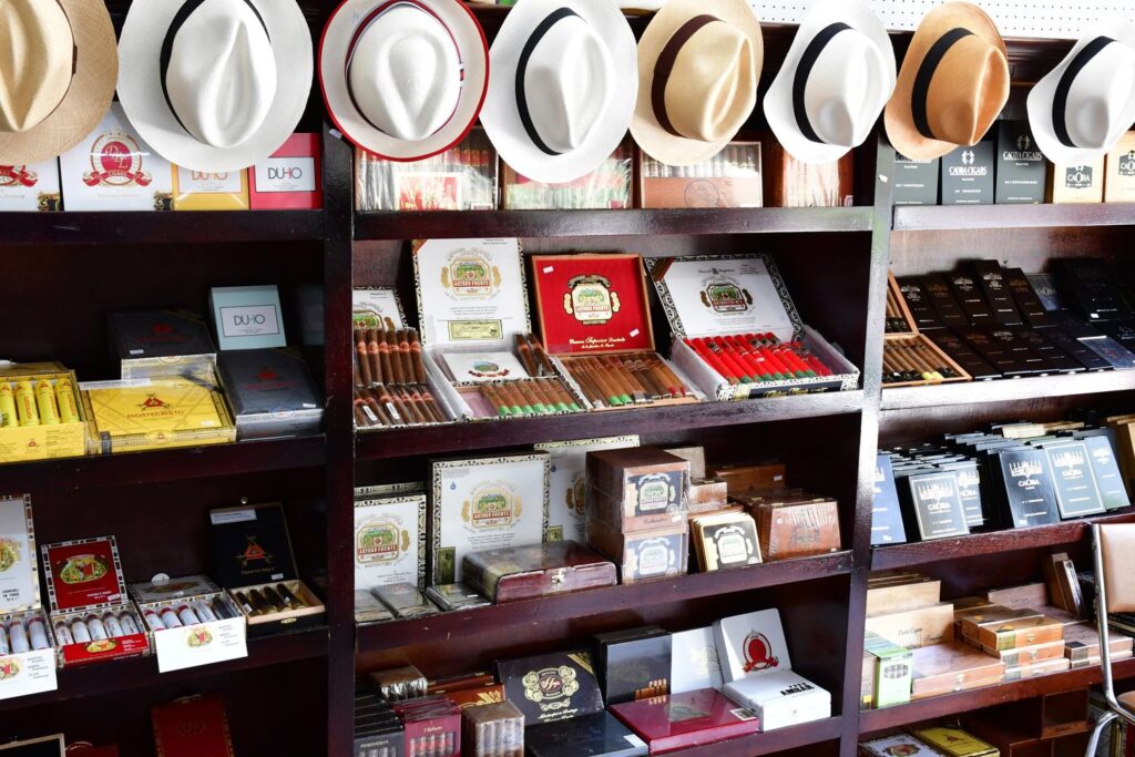 Shelves stocked with premium cigars and stylish hats in a shisha store in Tulsa, showcasing a variety of brands and packaging.