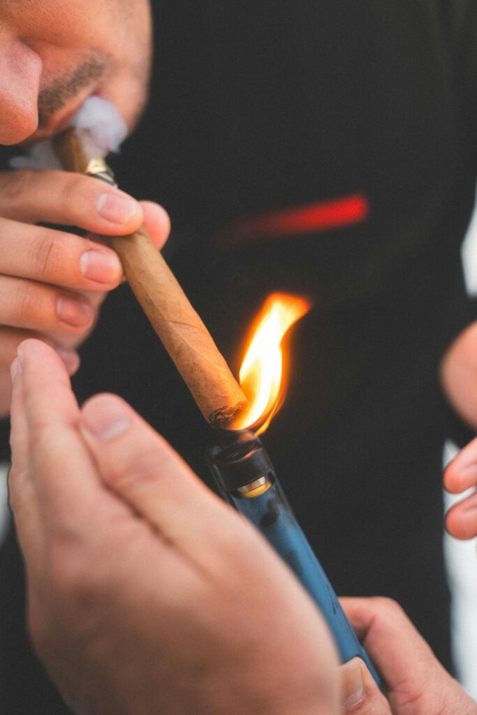 Close-up of lighting a high-quality cigar with a blue torch lighter at an inviting Cigar Shop Tulsa for ultimate relaxation.