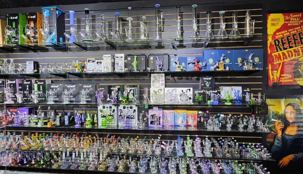 Colorful display of glass hookahs and accessories at Cigarette Shop Tulsa, featuring various brands and a vibrant poster.