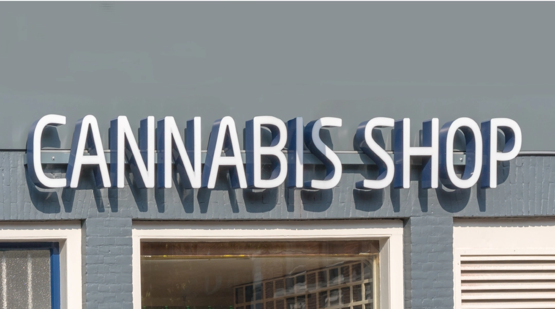 Large, white "CANNABIS SHOP" sign lettering on a gray brick building, a popular spot near the Tobacco Shop Tulsa.