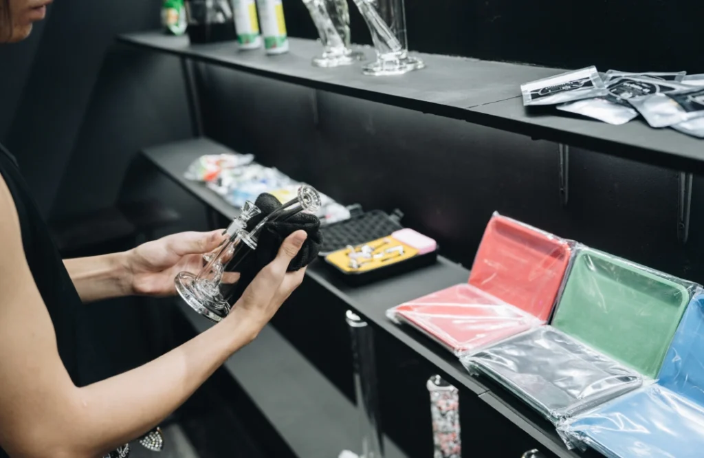 Customer inspecting glass pipes and various smoking accessories displayed on black shelves at the local Smoke Store Tulsa.