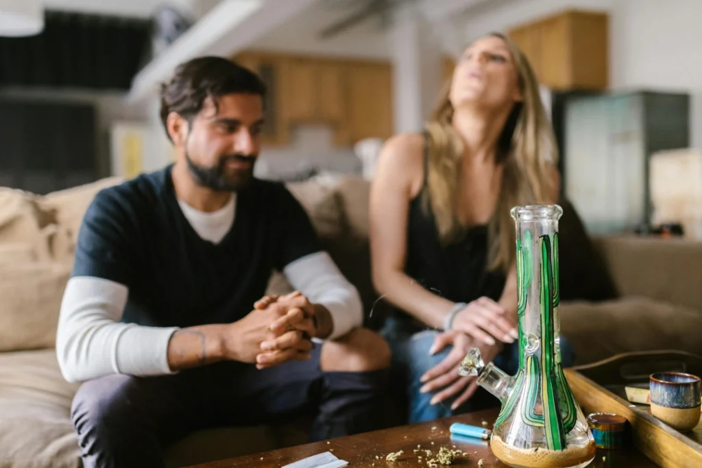 Couple on couch with green-accented bong on coffee table, relaxed social vaping scene for E-Cigarettes Tulsa marketing