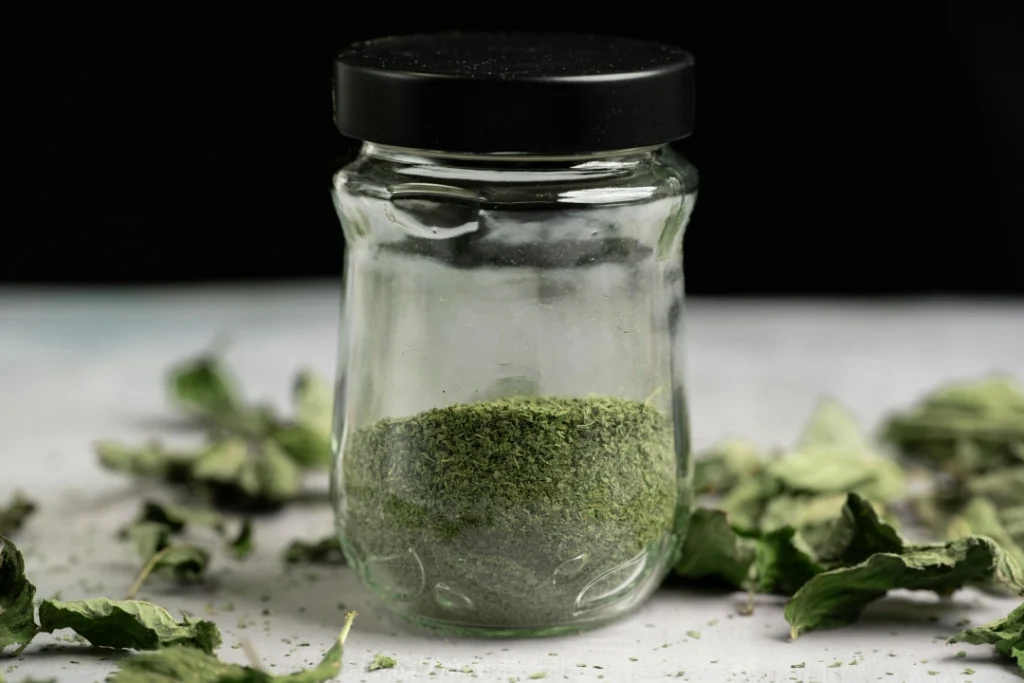 Dried green flakes and herbs in a glass jar, perfect for a specialty product available at a Tobacco Shop Tulsa.