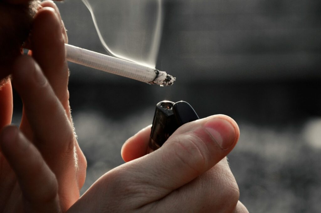 Close-up of a person lighting a cigarette with a lighter. All major brands available at your Cigarette Shop Tulsa.