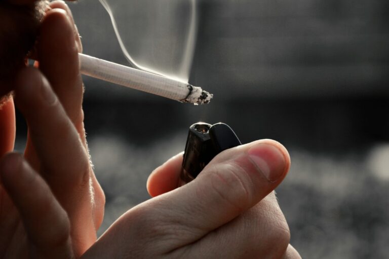 Close-up of a person lighting a cigarette with a lighter. All major brands available at your Cigarette Shop Tulsa.