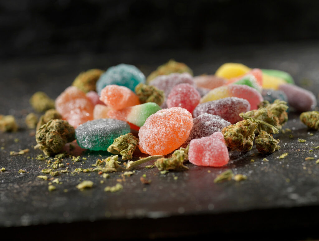 Assortment of colorful CBD gummies and hemp flower on a dark surface from the leading cbd shop tulsa.