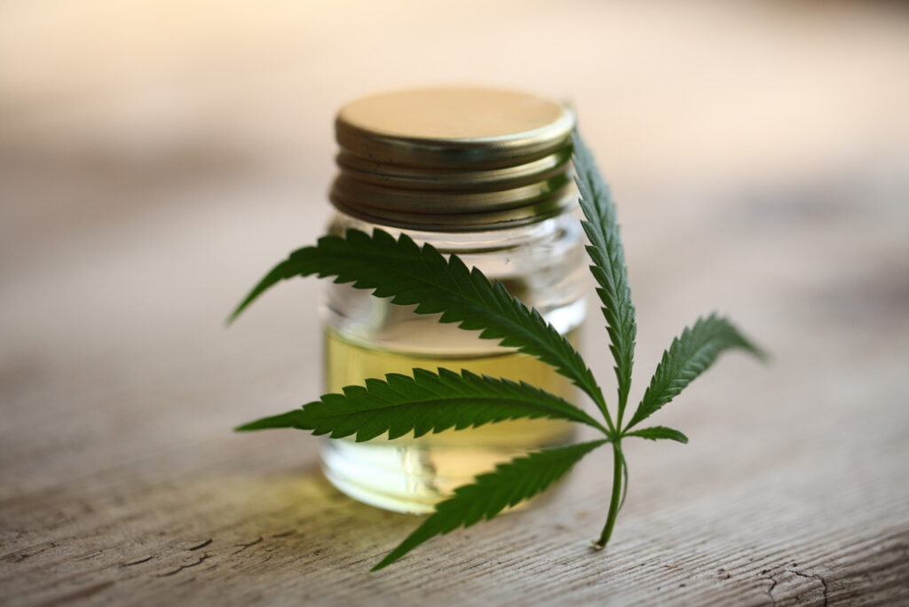 Clear jar of premium hemp extract at a cbd store tulsa displayed on a rustic wood surface with a cannabis leaf.