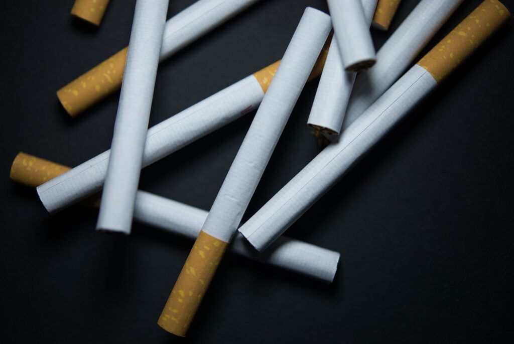 Scattered tobacco products at a cigarette shop Tulsa, showing filtered cigarettes against a dark background.