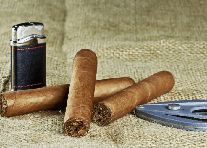 Premium hand-rolled cigars with a leather torch lighter and cutter on burlap at the best cigar shop Tulsa offers.