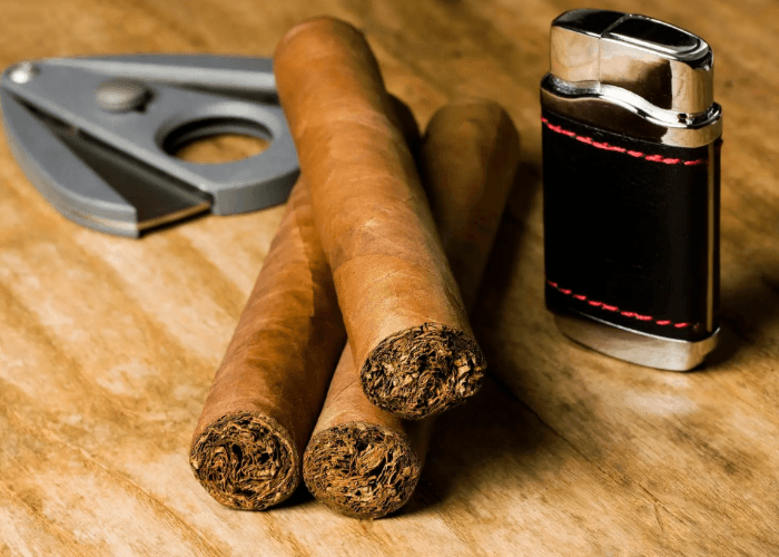 Close up of premium hand-rolled cigars, a metal cutter, and a luxury lighter from a top-rated cigar shop Tulsa hub.