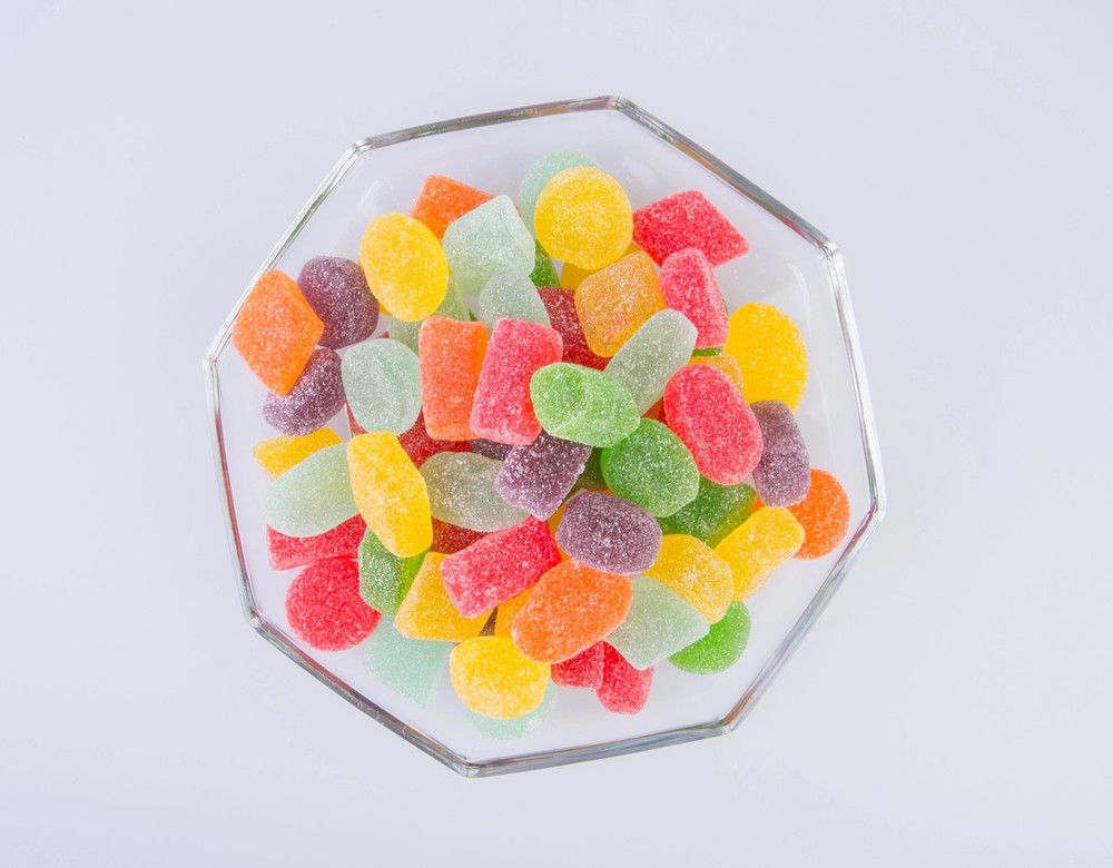 A glass bowl overflowing with assorted colorful Delta 8 gummies, from a leading delta 8 shop tulsa.