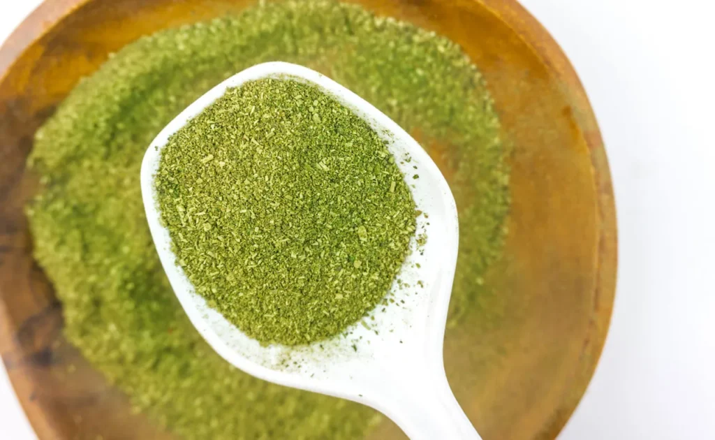 A white spoon scooping high quality green leaf powder sourced from a trusted premium kratom retail Tulsa vendor.